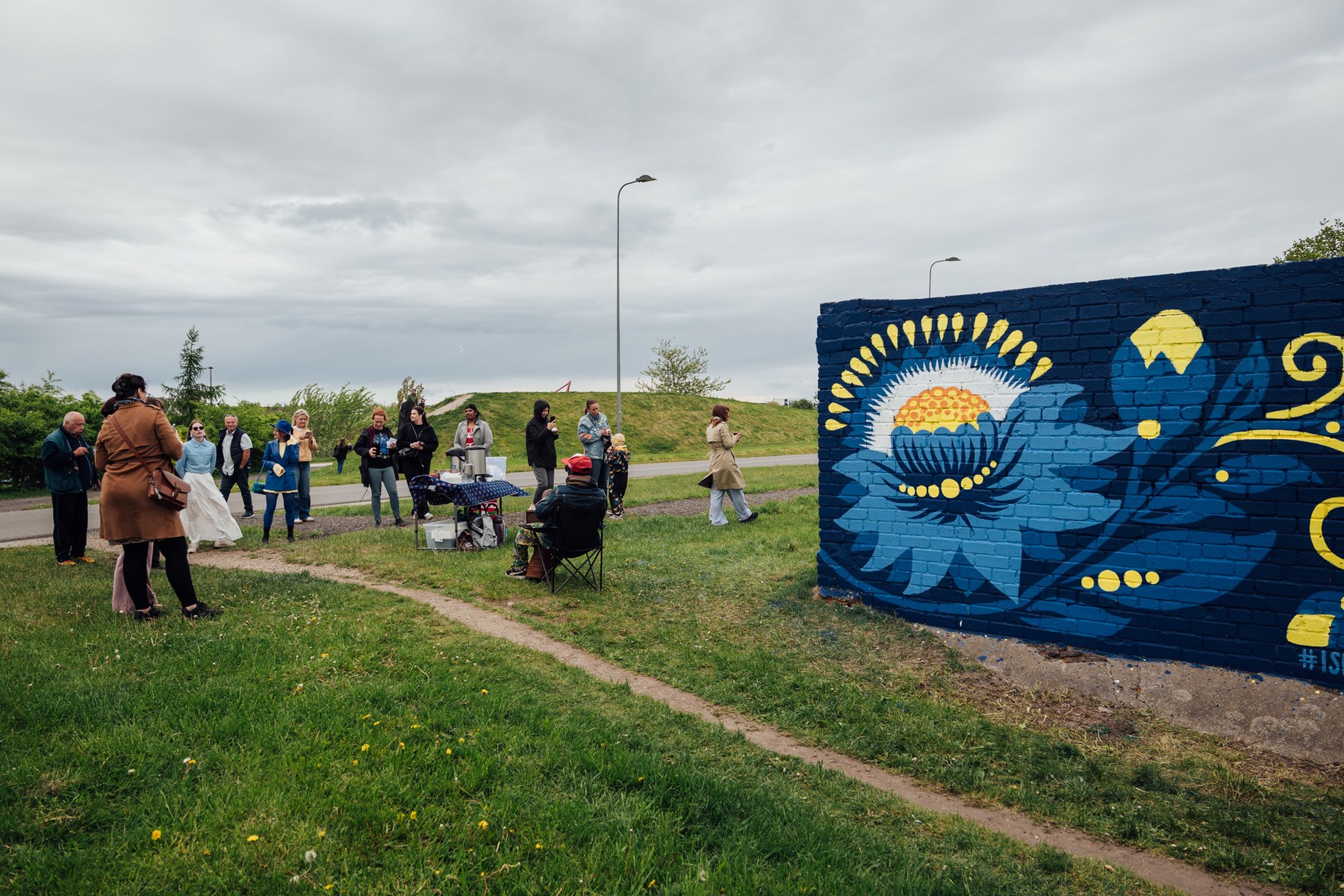 Rahvas kogunemas mööda rohust rada tänavakunstiteose juurde